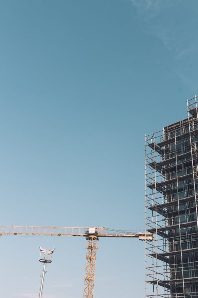 Construction crane against building with scaffolding